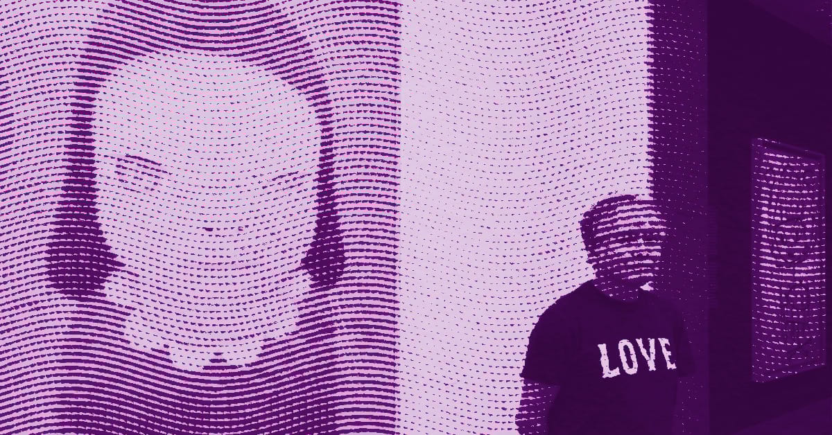 A man wearing a LOVE shirt stands near a large, stylized artwork of a face composed of horizontal dotted lines. The image is tinted purple and has a modern, digital art feel. © Illustration by ArtCritic.