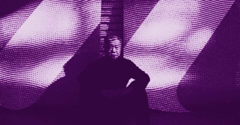 A person sits in front of a large screen displaying abstract, wavy purple and white patterns. The person is mostly in shadow, making their features hard to distinguish. © Illustration by ArtCritic.