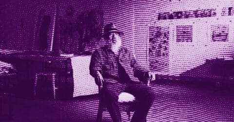 An elderly person with a beard sits on a chair in an art studio, surrounded by paintings and art supplies. The image is filtered in purple hues with a wavy, dotted overlay effect. © Illustration by ArtCritic.