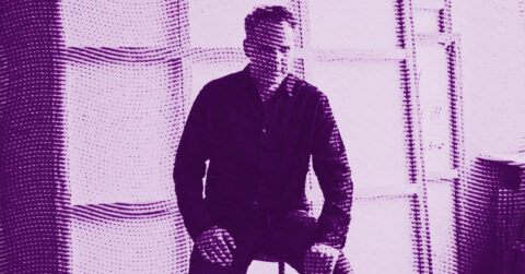 Andy Denzler in a dark shirt sits on a stool in a room with large windows, shown in a purple halftone effect. © Illustration by Art Critic.