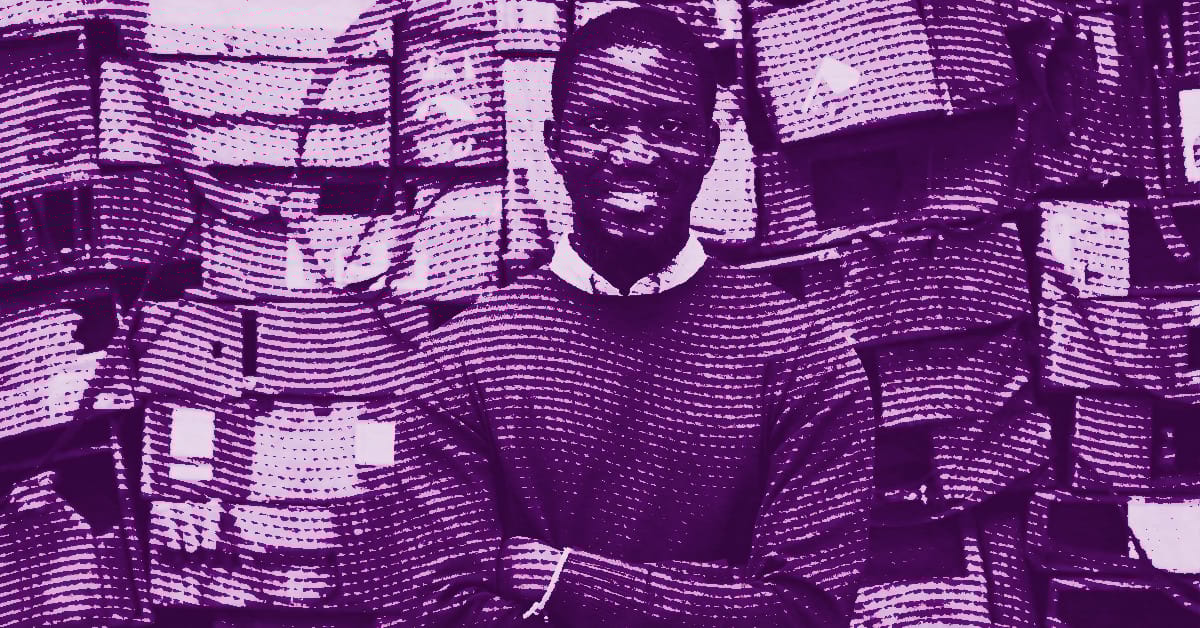 Ibrahim Mahama standing with arms crossed and smiling, in front of a background filled with many stacked bags. The image is filtered in purple tones. © Illustration by Art Critic.