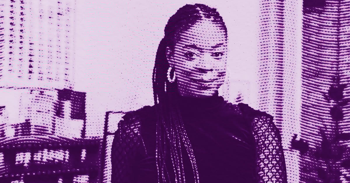 A stylized, purple-tinted image of Danielle Mckinney with long braids and hoop earrings, wearing a dark top, posing in front of urban skyscrapers. The image has a dotted, halftone effect. © Illustration by Art Critic.